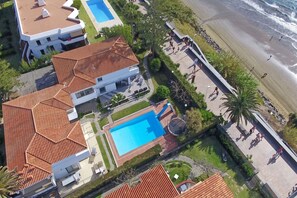 A residential area with a swimming pool, a beach, and a road with pedestrians. - GuestReady - Tarantos Sea View and Pool (Playa del Ingles)