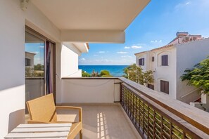 A balcony with a wicker chair, a view of the sea, and a building with shutters. - GuestReady - Tarantos Sea View and Pool (Playa del Ingles)