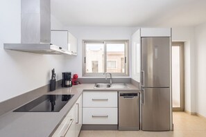 Eine moderne Küche mit einem Edelstahl-Kühlschrank, einer Spülmaschine und einem Fenster mit Blick auf Gebäude.