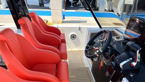 L'intérieur d'un bateau, avec des sièges rouges, un volant et un panneau de commande.