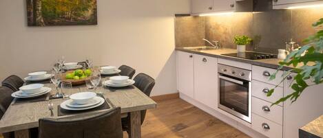 Una cocina moderna con armarios blancos, una mesa de comedor de madera y un cuadro en la pared.