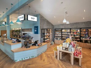 Un espacio comercial moderno con una zona de recepción, una tienda y estantes repletos de diversos productos.