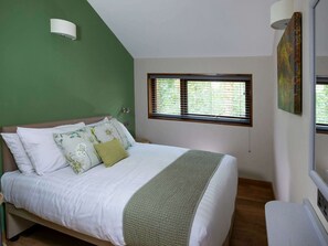 Un dormitorio con una cama, una ventana con persianas, una pared verde y un cuadro.