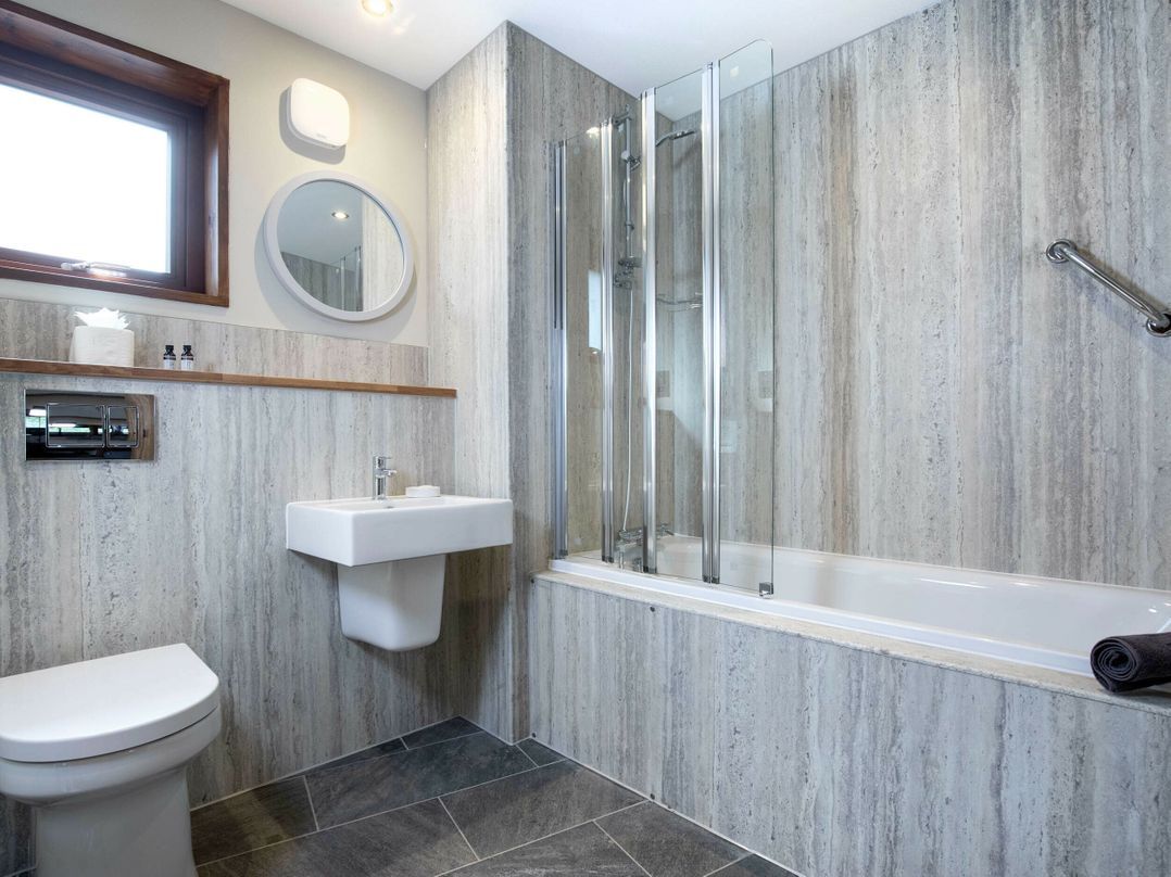 Un baño moderno con inodoro, lavamanos y ducha de vidrio.