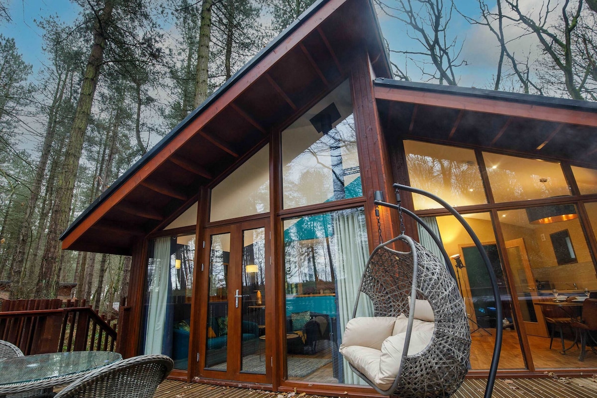 A modern cabin with large glass doors, a hanging chair, and a dining area.