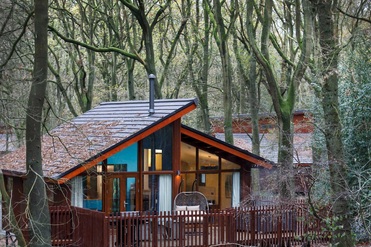 A cabin with a sloped roof, large windows, and a wooden deck.