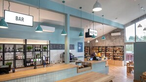 A bar area with a reception desk, shelves with bottles, and a wooden counter.
