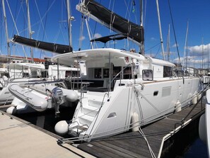 Un port de plaisance où est amarré un yacht blanc, doté d’une terrasse couverte, d’une cabine et d’une plateforme d’atterrissage pour hélicoptère.