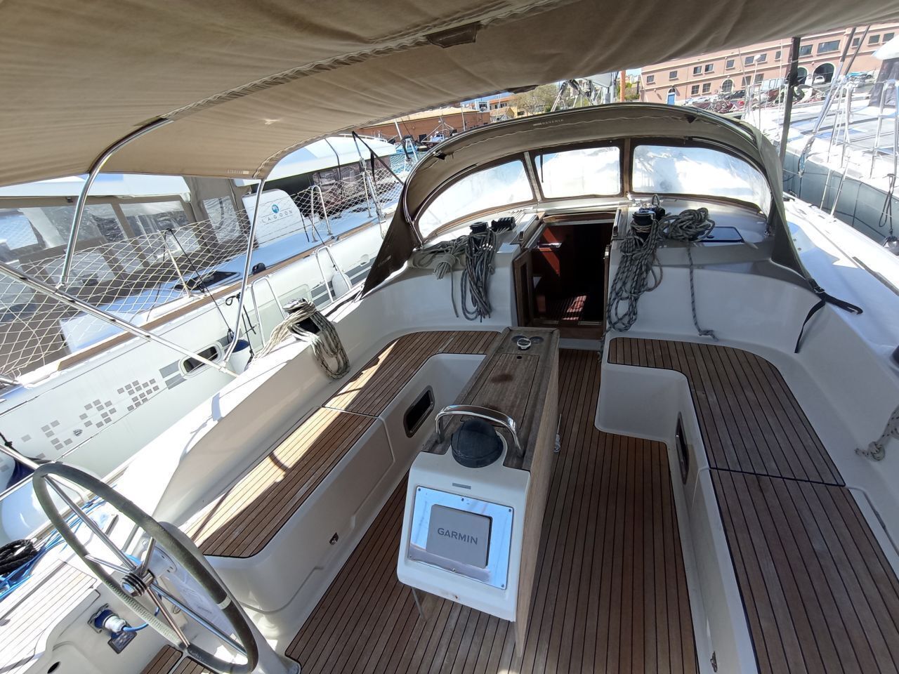 Das Deck eines Bootes mit einem Garmin-Gerät, einem Steuerlenkrad und einem Netzgeländer.