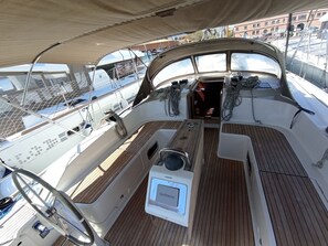 A boat's deck with a Garmin device, a steering wheel, and a netted railing. - Sun-Kissed Sailing Adventure in Islas Baleares, Mallorca (Palma)