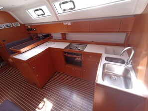 A compact galley with a sink, stove, and storage cabinets. - Sun-Kissed Sailing Adventure in Islas Baleares, Mallorca (Palma)