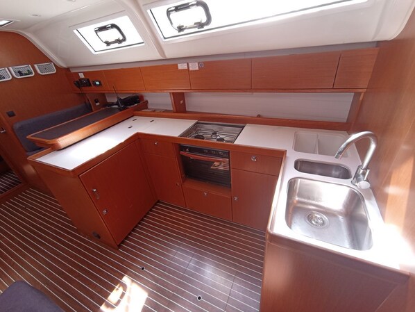 A compact galley with a sink, stove, and storage cabinets. - Sun-Kissed Sailing Adventure in Islas Baleares, Mallorca (Palma)