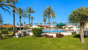 A resort with a swimming pool, palm trees, and beach chairs. - GuestReady - Los Arcos Outdoor Oasis (San Bartolomé de Tirajana)