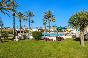 A resort with a swimming pool, palm trees, and beach chairs. - GuestReady - Los Arcos Outdoor Oasis (San Bartolomé de Tirajana)