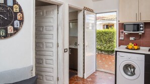 A laundry room with a washing machine, a microwave, and a clock with numbers on the wall. - GuestReady - Los Arcos Outdoor Oasis (San Bartolomé de Tirajana)