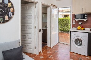 A laundry room with a washing machine, a microwave, and a clock with numbers on the wall. - GuestReady - Los Arcos Outdoor Oasis (San Bartolomé de Tirajana)