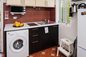 A compact kitchen with a washing machine, a sink, a microwave, and a small window. - GuestReady - Los Arcos Outdoor Oasis (San Bartolomé de Tirajana)