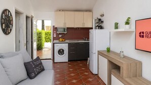 A compact living space with a sofa, a washing machine, a microwave, and a refrigerator. - GuestReady - Los Arcos Outdoor Oasis (San Bartolomé de Tirajana)