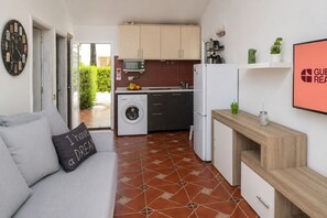 A compact living space with a sofa, a washing machine, a microwave, and a refrigerator. - GuestReady - Los Arcos Outdoor Oasis (San Bartolomé de Tirajana)