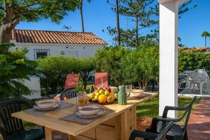 An outdoor dining area with a wooden table, chairs, and a variety of fruits and vegetables. - GuestReady - Los Arcos Outdoor Oasis (San Bartolomé de Tirajana)