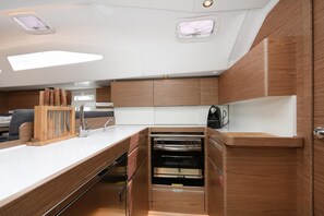 A compact kitchen with wooden cabinetry, a built-in oven, and a countertop with a knife block. - Sun-Kissed Sailing Adventure in Zadar, Croatia (Zadar)