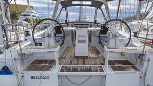 Un ponte di nave con timone, pannello di controllo e zone relax.