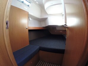 Un espacio interior reducido con una litera, una ventana pequeña y una puerta.