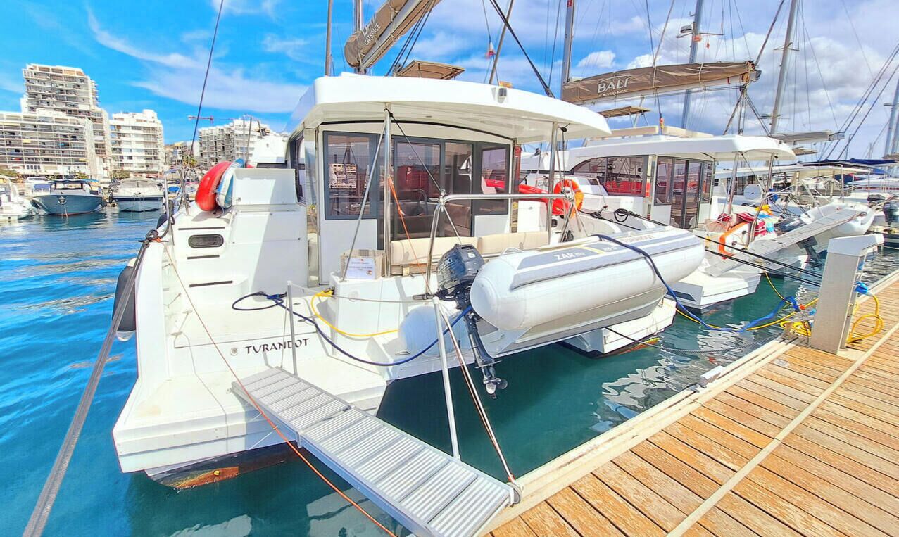 A marina with boats docked, a wooden deck, and a cityscape in the background.