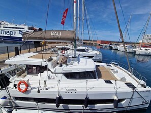 A marina with multiple boats, including a prominent white yacht named 'BALI' with 'CATANASTROUD' written on the side. - Sun-Kissed Sailing Adventure in the Majestic Islas Baleares (Sant Antoni de Portmany)