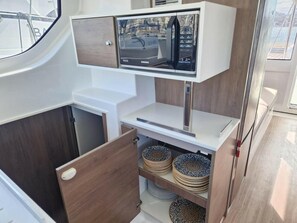 Une cuisine compacte équipée d’un four à micro-ondes, de meubles en bois et d’un petit plan de travail.