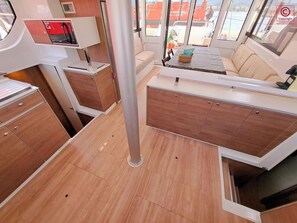 A boat interior with a dining area, seating, and a control panel. - Sun-Kissed Sailing Adventure in the Majestic Islas Baleares (Sant Antoni de Portmany)