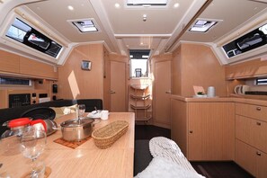 A compact kitchen with a dining area, equipped with a stove, microwave, and storage cabinets. - Sun-Kissed Sailing Adventure in Zadar, Croatia (Biograd na moru)