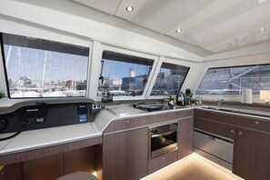 Une cuisine moderne équipée d’un système de navigation Raymarine, d’appareils électroménagers en acier inoxydable et de grandes fenêtres offrant une vue sur un port de plaisance.