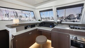 A boat's interior with a control panel, windows, a small stool, and a stove. - Sun-Kissed Sailing Adventure in Zadar, Croatia (Zadar)