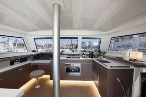 Eine moderne Küche mit Kochinsel, eingebautem Backofen und großen Fenstern mit Blick auf einen Hafen.