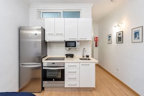 A compact kitchen with a refrigerator, oven, microwave, and white cabinetry. - GuestReady - Salvador Cuyas Beach Walk (Las Palmas de Gran Canaria)