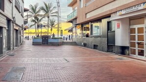 A building with a sign 'Canteras Playa Apartamentos' and a paved walkway with palm trees. - GuestReady - Salvador Cuyas Beach Walk (Las Palmas de Gran Canaria)