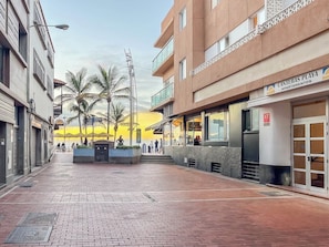 A building with a sign 'Canteras Playa Apartamentos' and a paved walkway with palm trees. - GuestReady - Salvador Cuyas Beach Walk (Las Palmas de Gran Canaria)