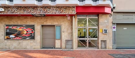 A building with a roulette wheel mural, a closed garage door, and a no parking sign.
