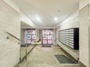 A modern interior with a staircase, a glass door entrance, and a wall-mounted mailbox. - GuestReady - Salvador Cuyas Beach Walk (Las Palmas de Gran Canaria)
