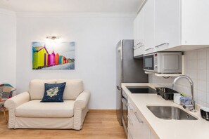 A compact kitchen with a sofa, a microwave, and a sink. - GuestReady - Salvador Cuyas Beach Walk (Las Palmas de Gran Canaria)