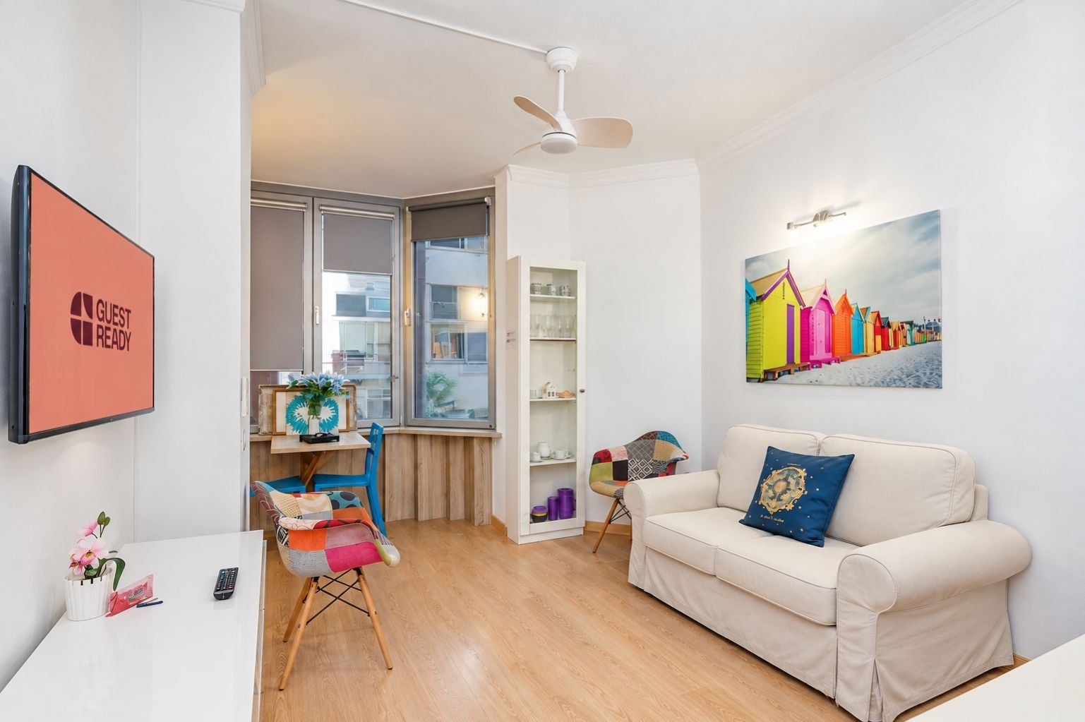 Una sala de estar moderna con un sofá, una mesita, una silla, una estantería y un cuadro en la pared.