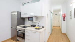 A compact kitchen with a refrigerator, oven, microwave, and sink. - GuestReady - Salvador Cuyas Beach Walk (Las Palmas de Gran Canaria)