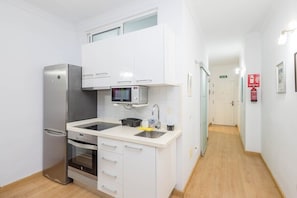 A compact kitchen with a refrigerator, oven, microwave, and sink. - GuestReady - Salvador Cuyas Beach Walk (Las Palmas de Gran Canaria)