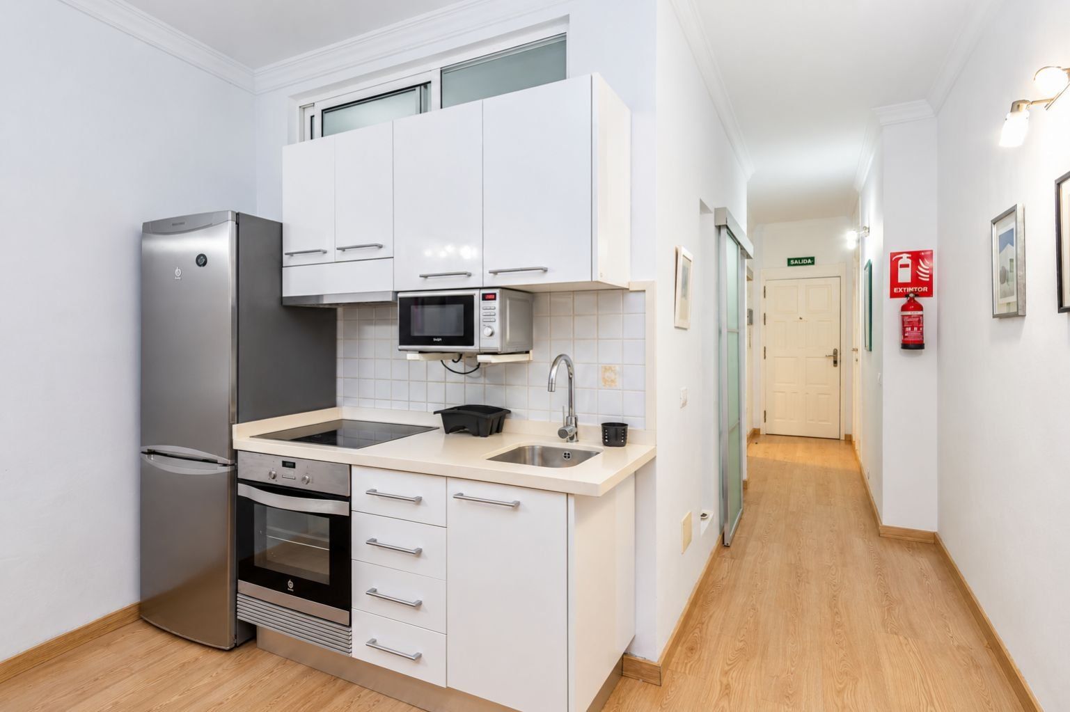 A compact kitchen with a refrigerator, microwave, oven, and sink.
