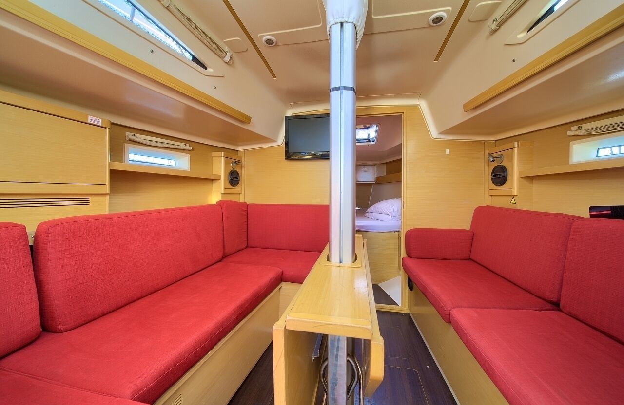 Une cabine dotée de sièges rembourrés de couleur rouge, d’un poteau central et d’un téléviseur fixé au mur.