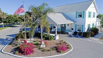 A white building with blue shutters, a flag, and a sign indicating a guest center.