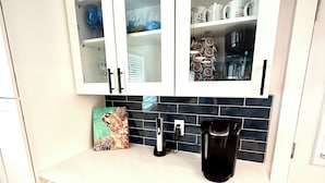 Una cocina con armarios blancos, una cafetera y un horno empotrado.