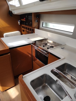 A compact galley kitchen with a stove, sink, and storage cabinets.