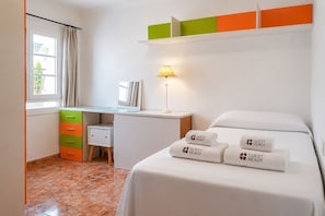 Une chambre d’hôtel avec un lit, un bureau doté d’une lampe, une fenêtre avec des rideaux et un ensemble de serviettes sur lesquelles est inscrit le texte « PRÊT POUR L’ARRIVÉE DU CLIENT ».